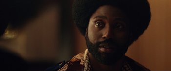 Movie still from “BlacKkKlansman” (2018), directed by Spike Lee – A person with a beard looking at the camera; Close Up shot, Over the shoulder angle