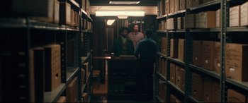 Movie still from “BlacKkKlansman” (2018), directed by Spike Lee – Three men are standing in a storage room talking; Wide shot, Over the shoulder angle