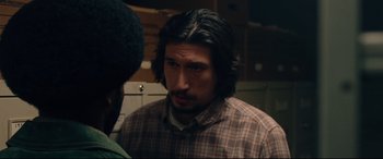 Movie still from “BlacKkKlansman” (2018), directed by Spike Lee – A man with long black hair standing next to another man; Close Up shot, Over the shoulder angle