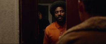 Movie still from “BlacKkKlansman” (2018), directed by Spike Lee – A man with a beard is standing in front of a mirror; Medium shot, Over the shoulder angle