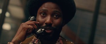 Movie still from “BlacKkKlansman” (2018), directed by Spike Lee – A man talking on a phone while wearing a hat; Close Up shot, Low angle