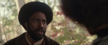 Movie still from “BlacKkKlansman” (2018), directed by Spike Lee – A person with a beard looking at the camera; Close Up shot, Over the shoulder angle