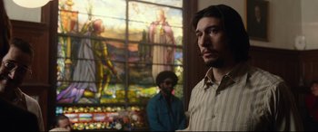 Movie still from “BlacKkKlansman” (2018), directed by Spike Lee – A man standing in front of a stained - glass window; Medium shot, Over the shoulder angle
