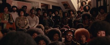 Movie still from “BlacKkKlansman” (2018), directed by Spike Lee – A group of people sitting in a room; Wide shot, High angle