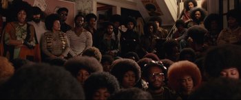 Movie still from “BlacKkKlansman” (2018), directed by Spike Lee – A group of people sitting in a room; Wide shot, High angle