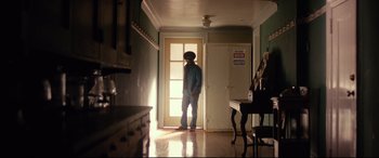 Movie still from “BlacKkKlansman” (2018), directed by Spike Lee – A man standing in a doorway in a room; Wide shot, Low angle