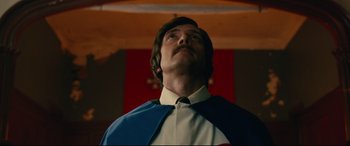 Movie still from “BlacKkKlansman” (2018), directed by Spike Lee – A man in a white shirt and blue and red tie looking upward; Medium shot, Low angle