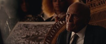 Movie still from “BlacKkKlansman” (2018), directed by Spike Lee – An older man in a suit and tie sitting in front of a woman; Close Up shot, Over the shoulder angle