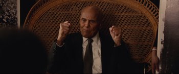 Movie still from “BlacKkKlansman” (2018), directed by Spike Lee – An older man in a suit and tie raising his hands in the air; Close Up shot, Low angle