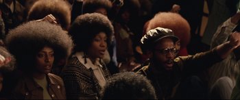 Movie still from “BlacKkKlansman” (2018), directed by Spike Lee – A group of people sitting in front of a crowd; Close Up shot, Over the shoulder angle