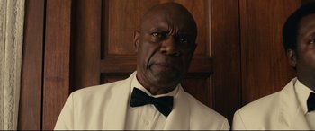 Movie still from “BlacKkKlansman” (2018), directed by Spike Lee – A man in a white suit and a black bow tie; Close Up shot, Low angle