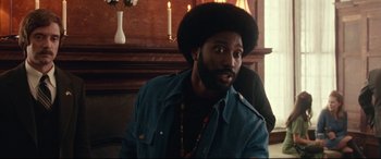 Movie still from “BlacKkKlansman” (2018), directed by Spike Lee – A man with a beard is sitting in front of a fireplace; Close Up shot, Over the shoulder angle