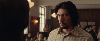 Movie still from “BlacKkKlansman” (2018), directed by Spike Lee – A man with long black hair standing in front of a group of people; Close Up shot, Over the shoulder angle