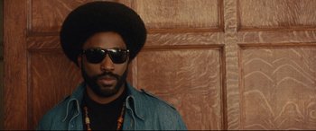 Movie still from “BlacKkKlansman” (2018), directed by Spike Lee – A man with a beard wearing sunglasses and a jean jacket; Close Up shot, Over the shoulder angle
