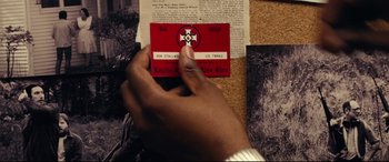 Movie still from “BlacKkKlansman” (2018), directed by Spike Lee – A hand is holding a red card with a cross on it; Extreme Close Up shot, High angle