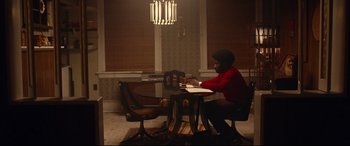 Movie still from “BlacKkKlansman” (2018), directed by Spike Lee – A man sitting at a table in front of a laptop; Wide shot, High angle