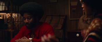 Movie still from “BlacKkKlansman” (2018), directed by Spike Lee – A man sitting at a table with a glass of wine in front of him; Medium shot, Over the shoulder angle