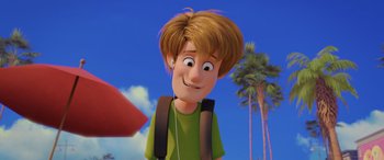 Movie still from “Scoob!” (2020), directed by Tony Cervone – A cartoon of a boy with a backpack and headphones; Close Up shot, Over the shoulder angle