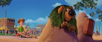 Movie still from “Scoob!” (2020), directed by Tony Cervone – A dog with long hair is sitting on a hill; Wide shot, Low angle