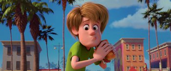 Movie still from “Scoob!” (2020), directed by Tony Cervone – A cartoon boy eating a hot dog on a bun; Close Up shot, High angle