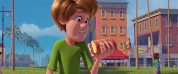 Movie still from “Scoob!” (2020), directed by Tony Cervone – A cartoon boy holding a hot dog in his hand; Medium shot, Over the shoulder angle
