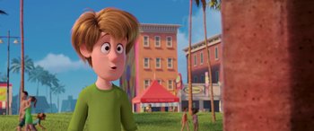 Movie still from “Scoob!” (2020), directed by Tony Cervone – A boy is standing in front of some buildings; Medium shot, Over the shoulder angle