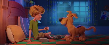Movie still from “Scoob!” (2020), directed by Tony Cervone – A boy sitting on the ground next to a dog; Wide shot, High angle