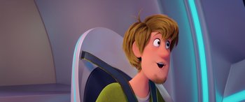 Movie still from “Scoob!” (2020), directed by Tony Cervone – A man with brown hair sitting in a car seat; Close Up shot, Over the shoulder angle