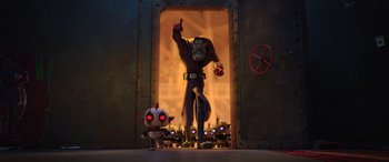 Movie still from “Scoob!” (2020), directed by Tony Cervone – A man standing in front of a door next to a small animal; Wide shot, Low angle