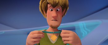 Movie still from “Scoob!” (2020), directed by Tony Cervone – A cartoon of a man holding a necklace with a gold medal on it; Close Up shot, Over the shoulder angle