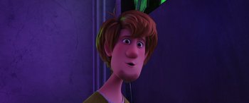 Movie still from “Scoob!” (2020), directed by Tony Cervone – A man with brown hair and green eyes is looking at the camera; Close Up shot, Over the shoulder angle