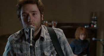 Movie still from “Scott Pilgrim vs. the World” (2010), directed by Edgar Wright – A man with a beard is singing into a microphone; Close Up shot, Over the shoulder angle