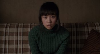 Movie still from “Scott Pilgrim vs. the World” (2010), directed by Edgar Wright – A woman sitting on top of a couch wearing a green sweater; Medium shot, High angle