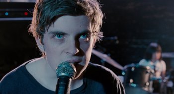 Movie still from “Scott Pilgrim vs. the World” (2010), directed by Edgar Wright – A man with blue eyes is holding a microphone; Close Up shot, Over the shoulder angle