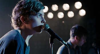 Movie still from “Scott Pilgrim vs. the World” (2010), directed by Edgar Wright – A man is singing into a microphone while another man watches; Close Up shot, Over the shoulder angle