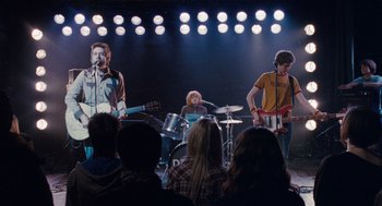 Movie still from “Scott Pilgrim vs. the World” (2010), directed by Edgar Wright – A group of people on a stage with lights in the background; Wide shot, High angle