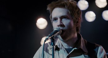 Movie still from “Scott Pilgrim vs. the World” (2010), directed by Edgar Wright – A man with spiky red hair is singing into a microphone; Close Up shot, Over the shoulder angle