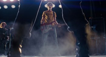 Movie still from “Scott Pilgrim vs. the World” (2010), directed by Edgar Wright – A young man holding a guitar in the middle of a stage; Wide shot, Low angle