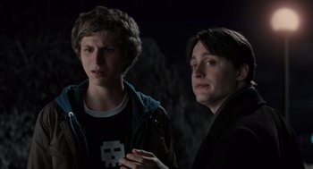 Movie still from “Scott Pilgrim vs. the World” (2010), directed by Edgar Wright – Two young men standing next to each other in the dark; Medium shot, Over the shoulder angle