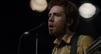 Movie still from “Scott Pilgrim vs. the World” (2010), directed by Edgar Wright – A man with a beard is singing into a microphone; Close Up shot, Low angle
