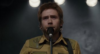 Movie still from “Scott Pilgrim vs. the World” (2010), directed by Edgar Wright – A man with a beard is singing into a microphone; Close Up shot, Over the shoulder angle