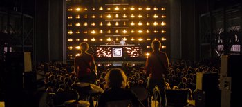 Movie still from “Scott Pilgrim vs. the World” (2010), directed by Edgar Wright – Two people standing in front of an audience in front of lights; Extreme Wide shot, Overhead angle