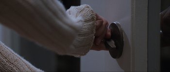 Movie still from “Scream” (1996), directed by Wes Craven – A person is holding the handle of a door knob; Extreme Close Up shot, High angle