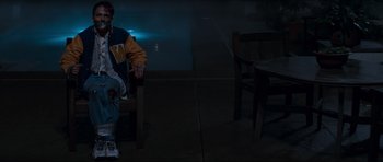 Movie still from “Scream” (1996), directed by Wes Craven – A man sitting on a bench in a dark room; Wide shot, High angle