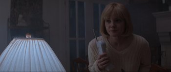 Movie still from “Scream” (1996), directed by Wes Craven – A woman holding a remote control in her hand; Medium shot, Low angle