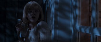 Movie still from “Scream” (1996), directed by Wes Craven – A woman in a white sweater standing next to a wall; Medium shot, Low angle