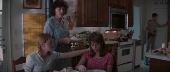 Movie still from “Scream” (1996), directed by Wes Craven – Two women and a child in a kitchen; Medium shot, Over the shoulder angle