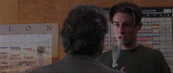 Movie still from “Scream” (1996), directed by Wes Craven – A man holding a knife in front of another man in a room; Close Up shot, Over the shoulder angle