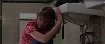 Movie still from “Scream” (1996), directed by Wes Craven – A woman sitting on a toilet in a bathroom; Medium shot, Low angle