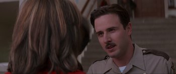 Movie still from “Scream” (1996), directed by Wes Craven – A man with a mustache talking to a woman in front of a staircase; Close Up shot, Low angle